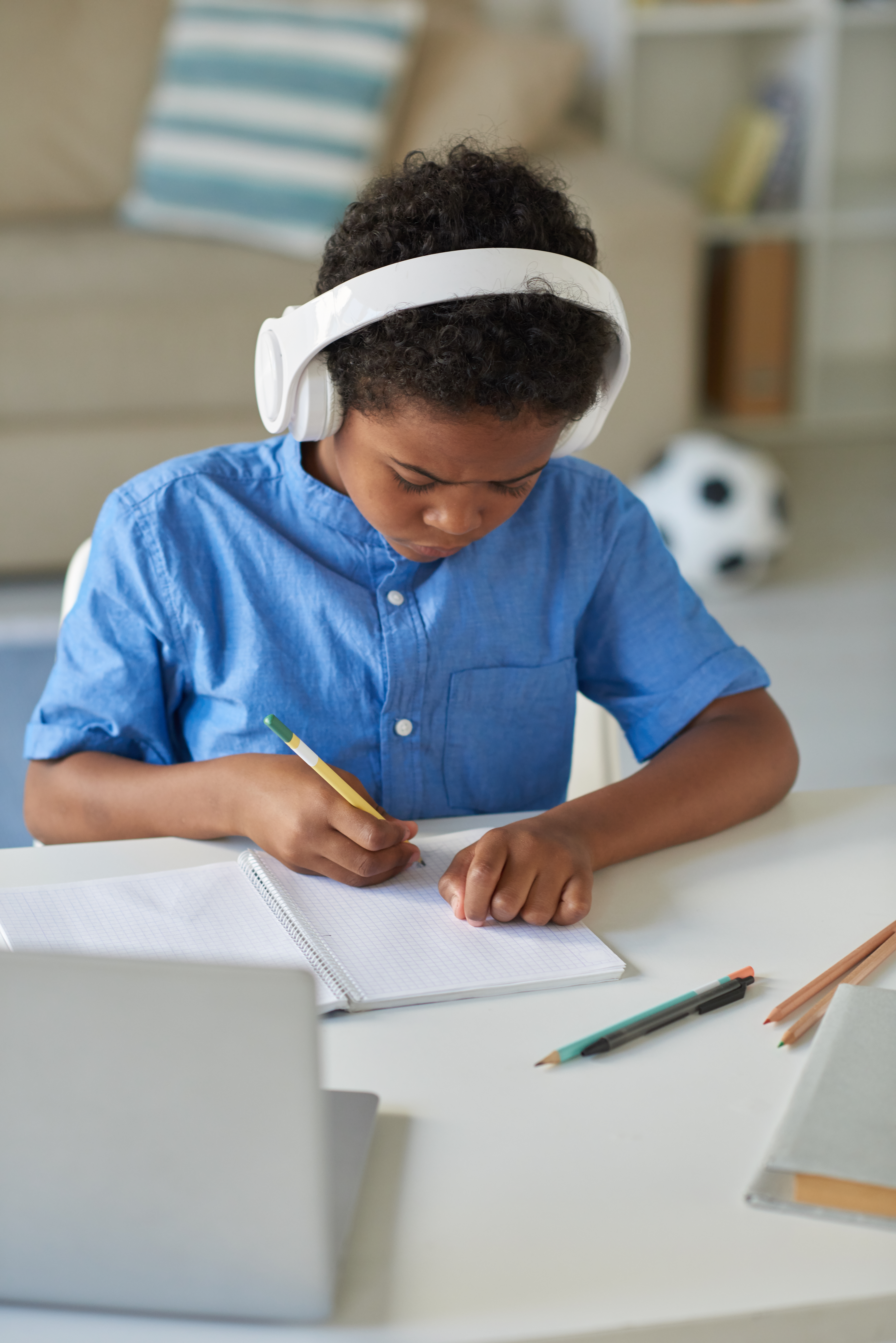 Student wearing headphones and writing in a notebook while learning